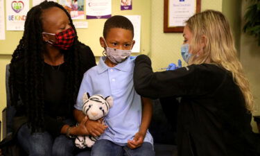 The next step in vaccinating children is families finding the nearest dose. Tyann Davis holds her son Cameron Davis' hand as IHA Plymouth Pediatrics Medical Assistant Madison Peterson gives him the Pfizer Covid-19 vaccine.