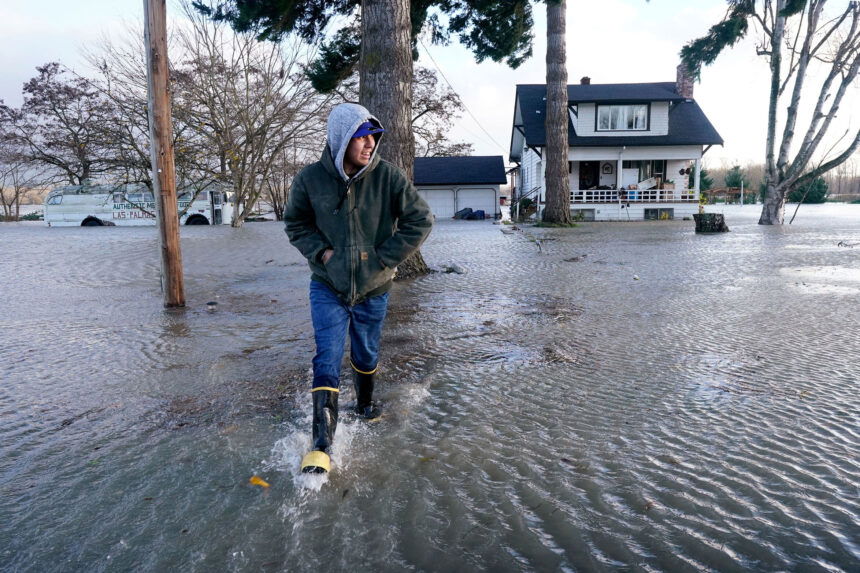 Benjamin Lopez steps from floodwater surrounding his parents home Monday in Sedro-Woolley