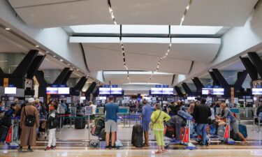 Travelers queue at a check-in counter at OR Tambo International Airport in Johannesburg on November 27