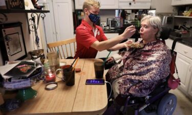 Personal care worker Andrew Wolfram (left) helps Karen Foxgrover eat lunch at her Downtown Madison apartment. Foxgrover