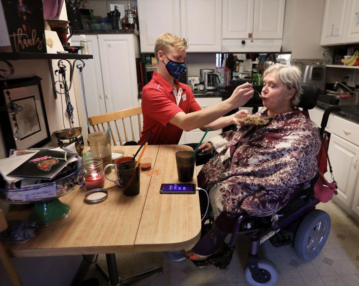 <i>Wisconsin State Journal</i><br/>Personal care worker Andrew Wolfram (left) helps Karen Foxgrover eat lunch at her Downtown Madison apartment. Foxgrover