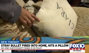 A woman points to bullet hole in a pillow in her Foley