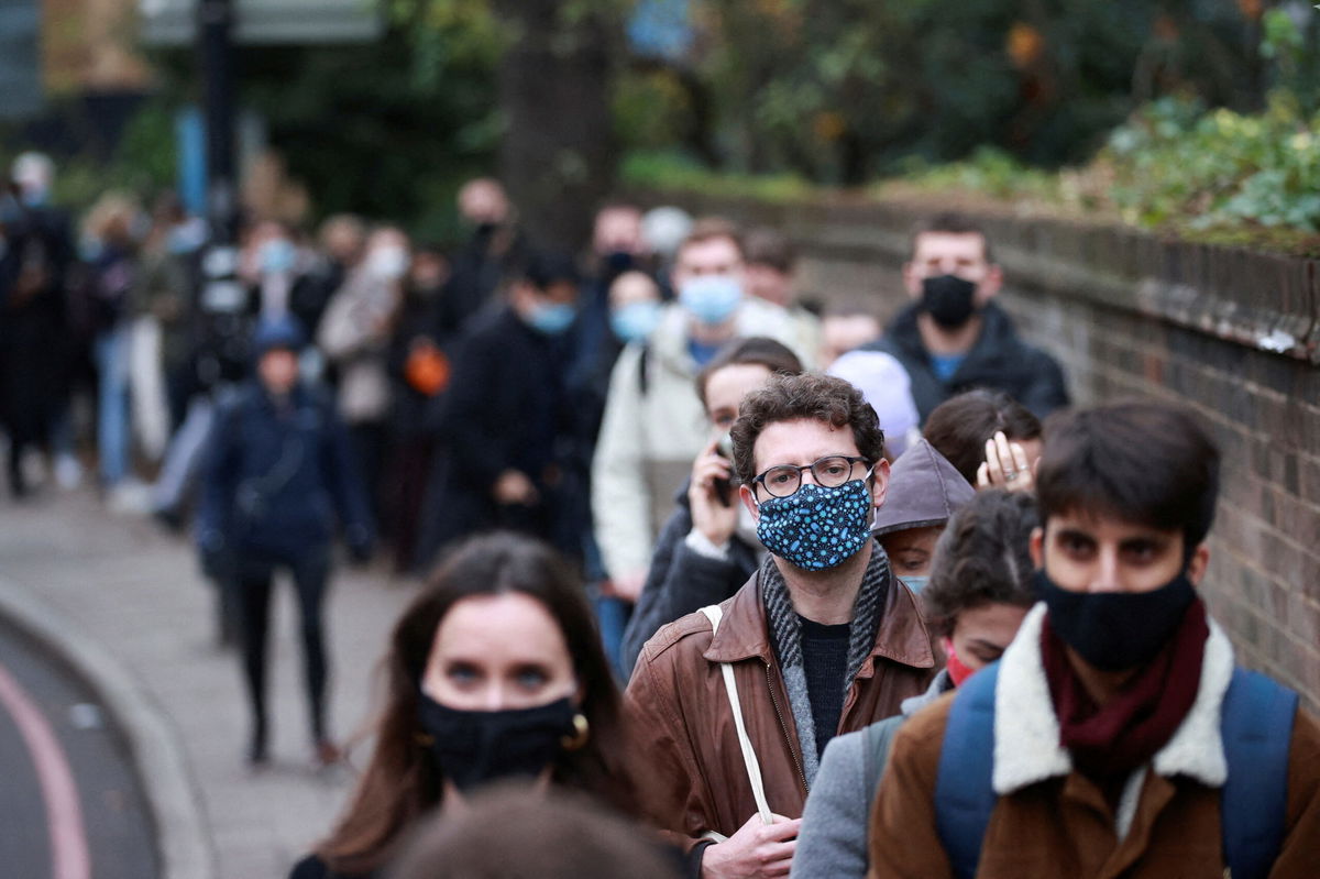 <i>HANNAH MCKAY/REUTERS</i><br/>People queue for their booster dose outside a coronavirus disease (COVID-19) vaccination centre in London