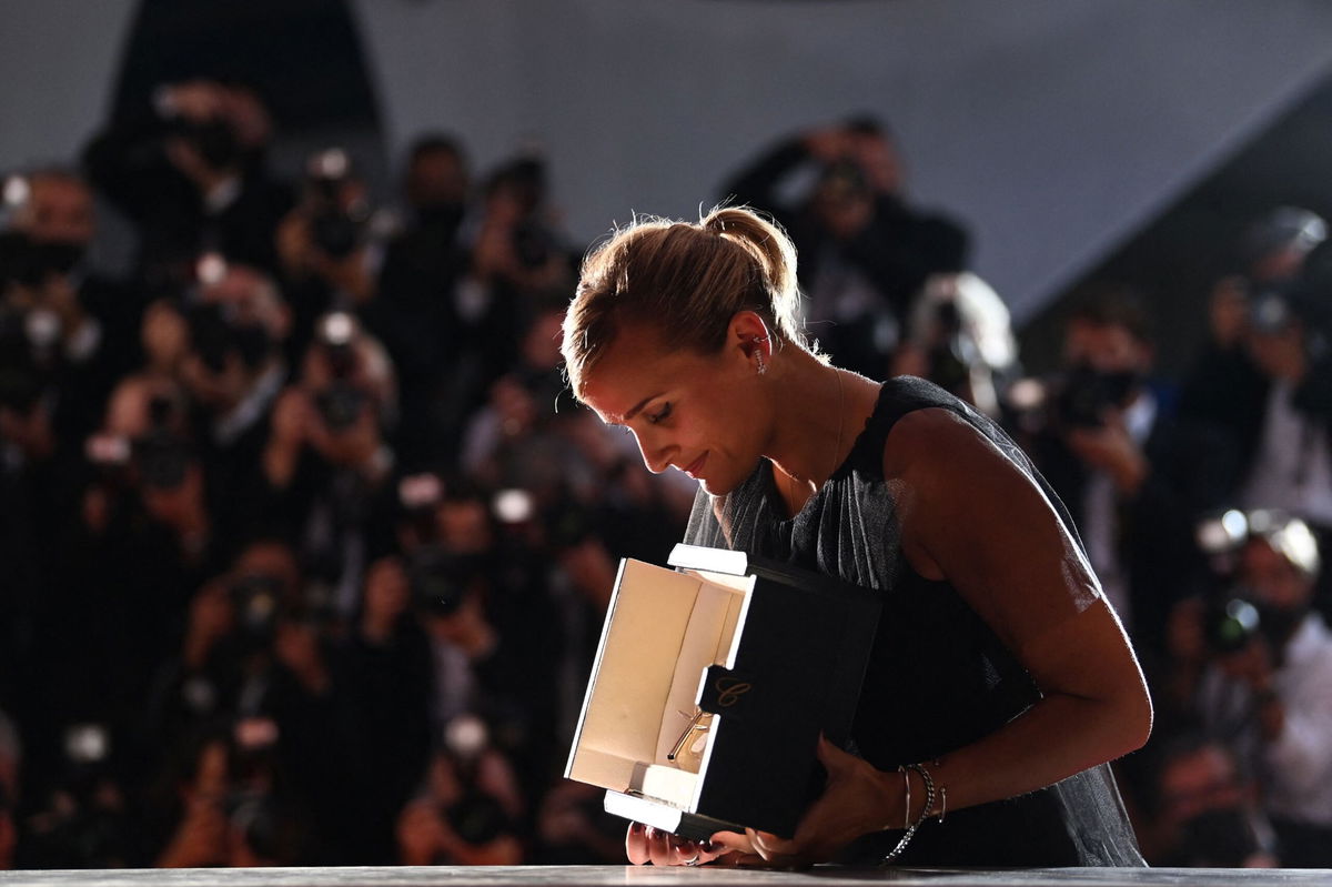 <i>CHRISTOPHE SIMON/AFP/AFP via Getty Images</i><br/>French director Julia Ducournau looks at her Palme d'Or for 