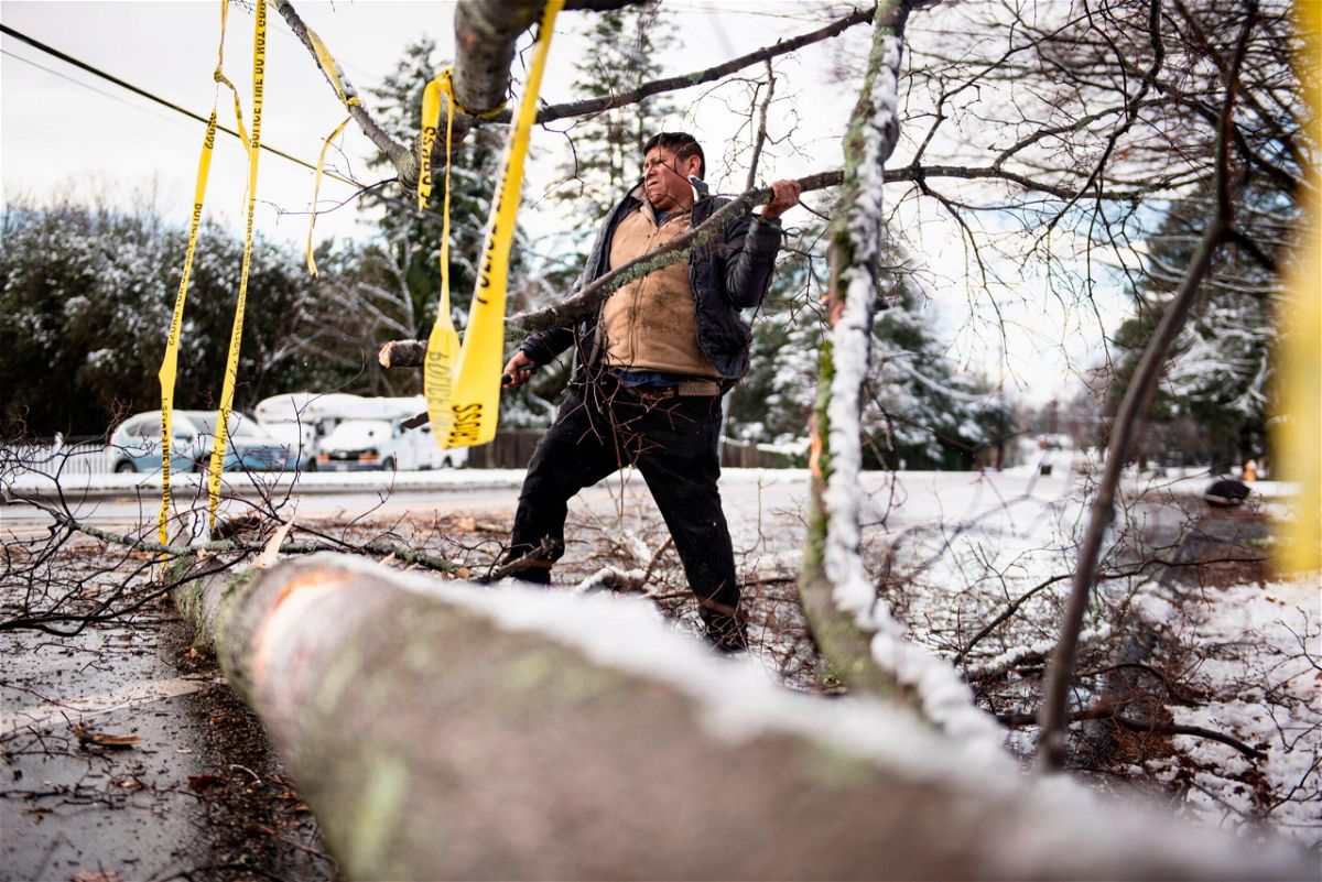 <i>Allison Lee Isley/Winston-Salem Journal/AP</i><br/>Galberto Castro cleans up the debris from a fallen tree in front of his home along Polo Road on January 3