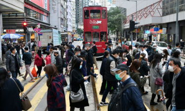 People wearing face masks cross a street in Hong Kong on December 21.