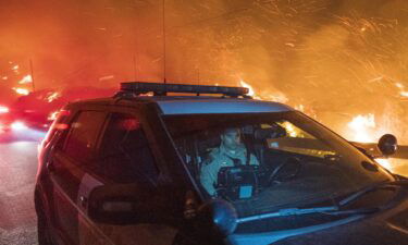 A California Highway Patrol officer drives south on Highway 1 as the Colorado Fire burns near Big Sur