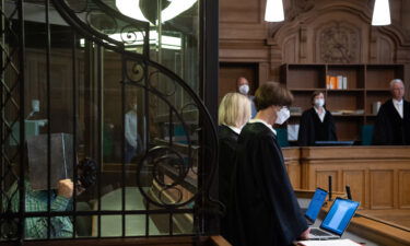 The defendant accused of murdering a man with "cannibalistic motives" sits in a courtroom holding cardboard in front of his face in Berlin in August 2021.