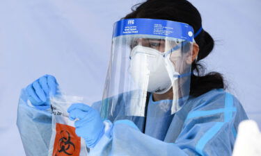 A healthcare worker places a Covid-19 PCR test vial into a bag for transportation at a Reliant Health Services testing site in Hawthorne