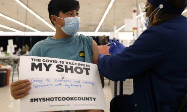 A teenager holds a sign in support of Covid-19 vaccinations as he receives his first Pfizer dose in May 2021 in Des Plaines