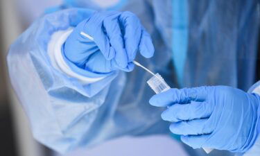 A healthcare worker places a test swab into a solution for a PCR Covid-19 test at a testing site in Hawthorne