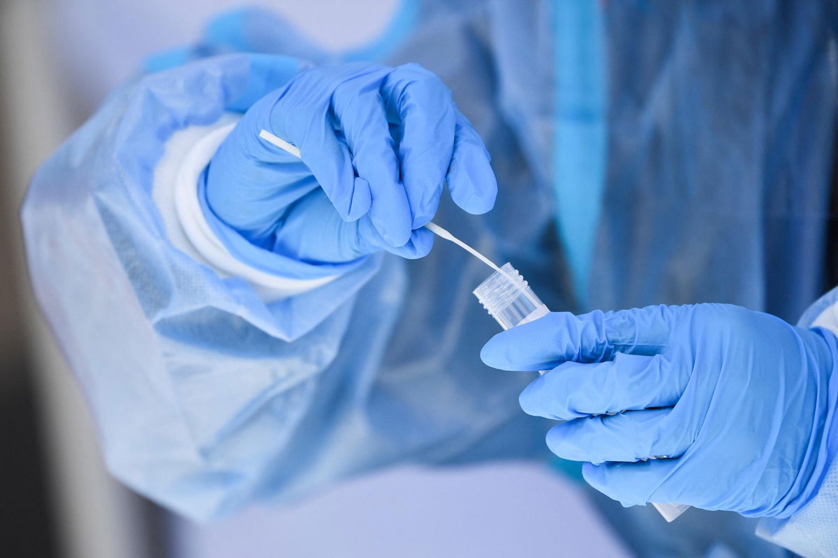 <i>PATRICK T. FALLON/AFP/Getty Images</i><br/>A healthcare worker places a test swab into a solution for a PCR Covid-19 test at a testing site in Hawthorne