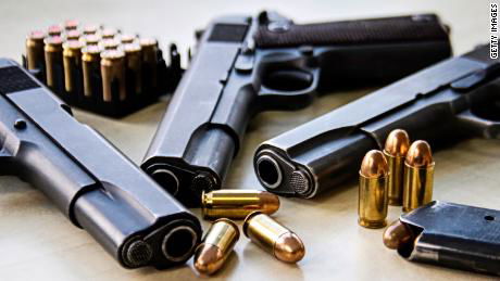 Three pistols laying on table with bullets