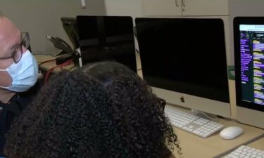 Los Angeles Police Department Chief Michel Moore looks on as a Dorsey High School student explains her project.