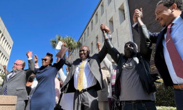 The family of Ahmaud Arbery and attorneys raise their arms in victory Tuesday outside the federal courthouse in Brunswick