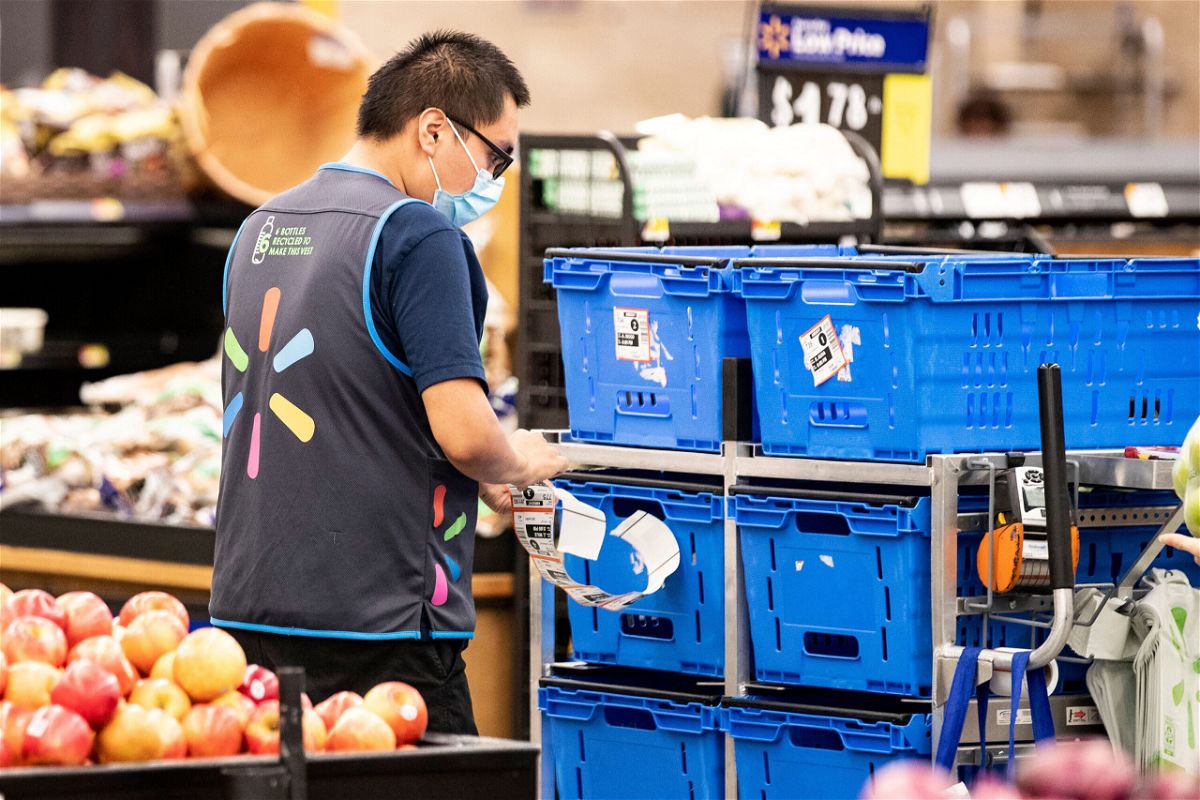 <i>Etienne Laurent/EPA-EFE/Shutterstock</i><br/>Walmart drops mask mandate for vaccinated employees. A Walmart employee here wears a mask as he works in Burbank