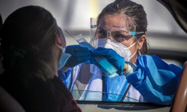 A healthcare worker Desirae Velasquez administers a Covid-19 test to Maria Lemus at a testing facility in Los Angeles