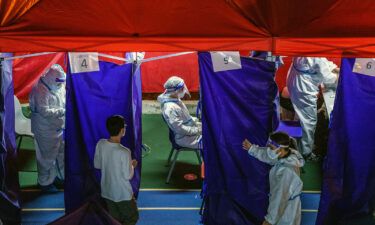 Healthcare workers attend to patients at a Covid-19 testing site set up outside a residential building placed under lockdown in Hong Kong