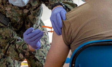 Hospital Corpsman 3rd Class Joseph Casassa administers a Covid-19 vaccine to Logistics Specialist Seaman Rix Zhang.