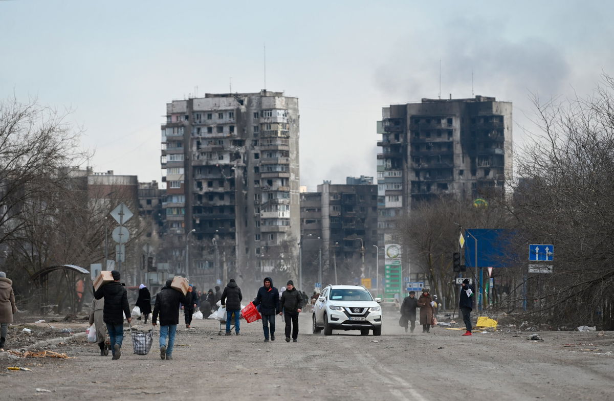 <i>Maksim Blinov/Sputnik/AP</i><br/>Refugees carrying their personal belongings leave Mariupol. While some have been able to leave