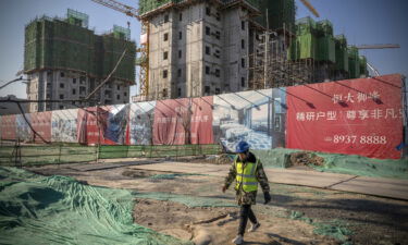 A worker walks past unfinished apartment buildings at the construction site of a China Evergrande Group development in Beijing