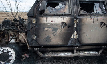 A burnt-out Russian Tigr fighting vehicle sits along a road in Mykolaiv