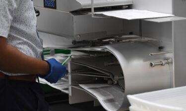 Election workers are seen loading ballots into the vote counting machine on election day 2020 at the Broward County Supervisor of Elections office during the 2020 Presidential Election