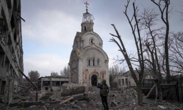 A Ukrainian serviceman takes a photograph of a damaged church after shelling in a residential district in Mariupol