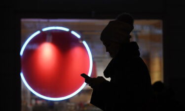 A woman is silhouetted as she walks past a shop