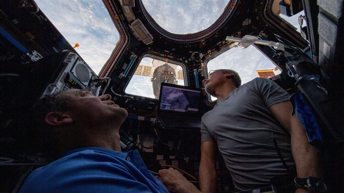 <i>NASA</i><br/>NASA astronauts Thomas Marshburn and Mark Vande Hei peer at the Earth below from inside the International Space Station's cupola. The Soyuz MS-19 crew ship can be seen docked outside the window.