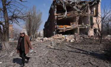 A woman walks past building damaged by shelling in Mariupol on Sunday.