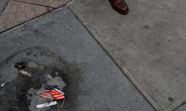 A protective face mask imprinted with the U.S. flag lays on the ground.