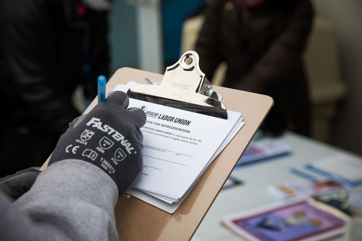 <i>Michael Nagle/Bloomberg/Getty Images</i><br/>An Amazon employee signs a labor union authorization for representation form outside the Amazon LDJ5 fulfillment center in the Staten Island borough of New York