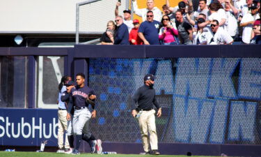 Oscar Mercado of the Cleveland Guardians is restrained as fans throw items on to the field following the New York Yankees win at Yankee Stadium on Saturday in New York City.