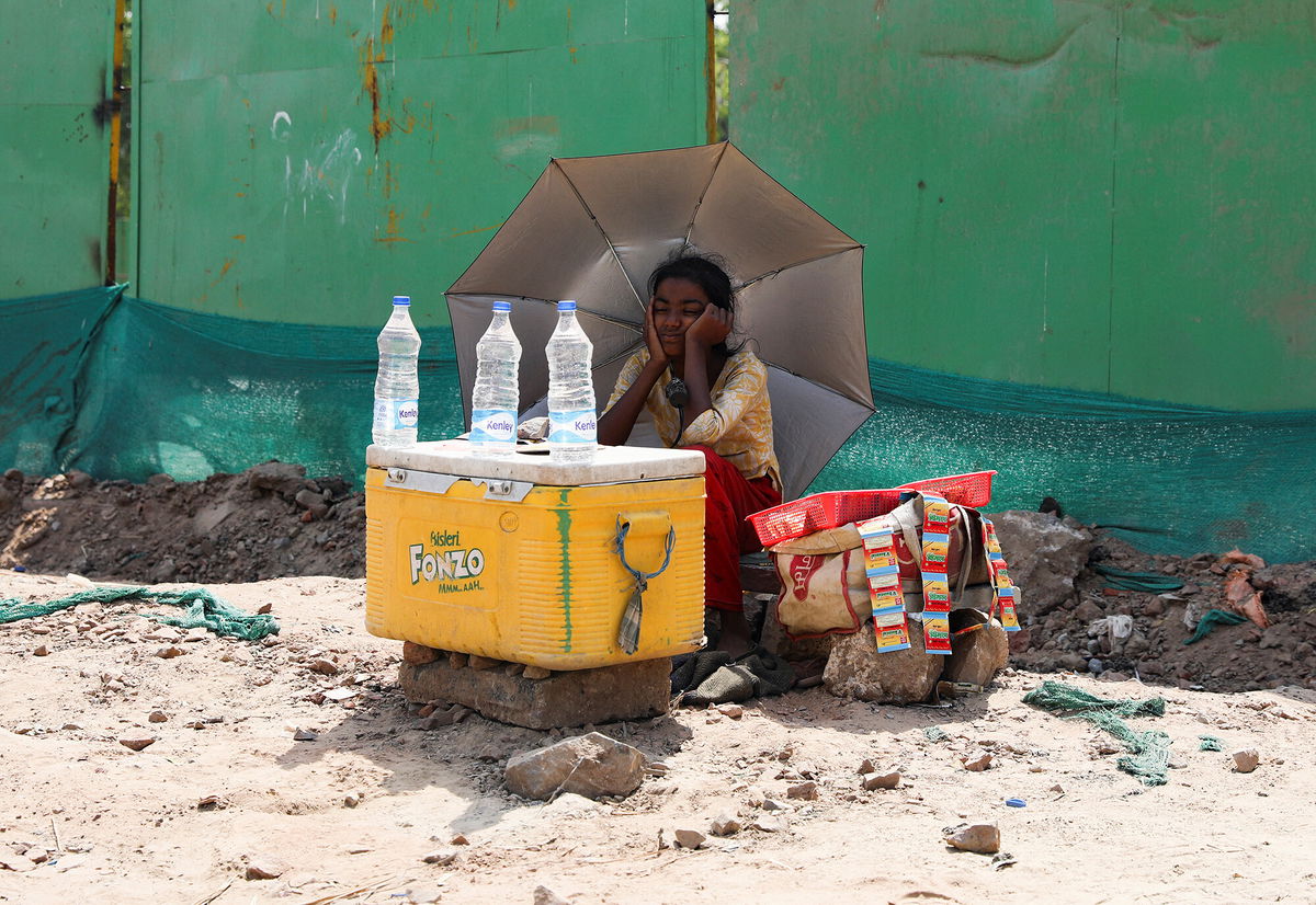 <i>Anushree Fadnavis/Reuters</i><br/>A girl selling water uses an umbrella to protect herself from the sun during a heat wave in New Delhi