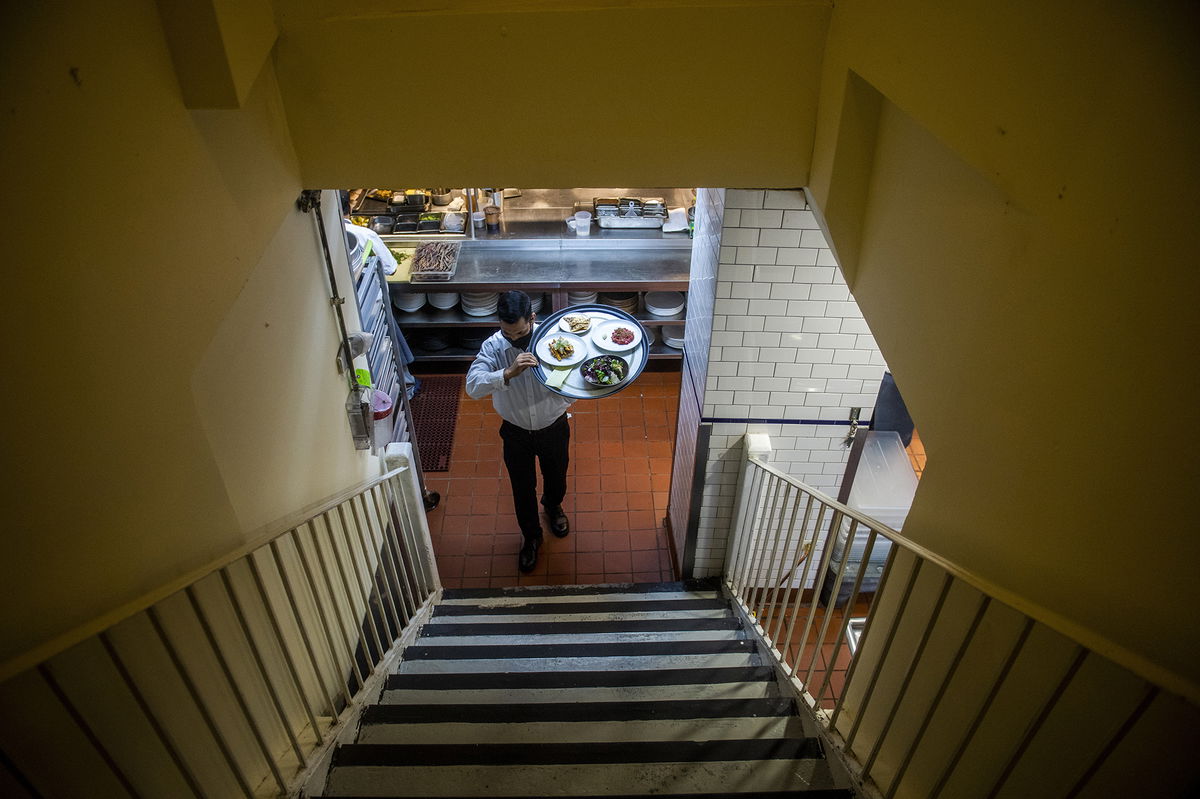 Muhammad Rahman delivers orders at Gotham restaurant on Tuesday, Dec. 14, 2021, in New York. When COVID-19 tore through the United States in March 2020, the recession it caused was brutal yet brief. Yet for much of 2021, the recovery was undermined by new threats: A surge in inflation that shrank the value of paychecks, hurt the least advantaged Americans most and posed a political threat to President Joe Biden and Democrats in Congress. (AP Photo/Brittainy Newman)