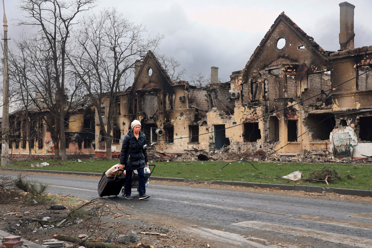 <i>Alexei Alexandrov/AP</i><br/>A woman pulls her bags past houses damaged in Mariupol