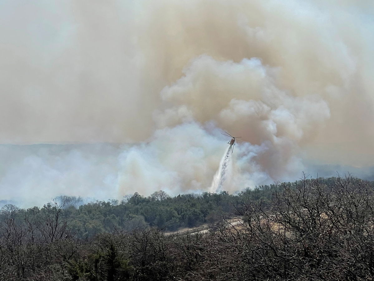 <i>Twitter/@johnnyhaysmd/Reuters</i><br/>A firefighting helicopter makes a water drop on the Eastland Complex wildfire near Rising Star