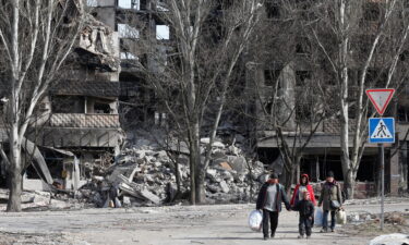 Local residents walk past an apartment building destroyed during the Ukraine-Russia conflict in Mariupol