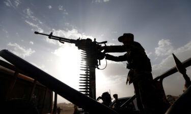 A Shiite Houthi rebel stands on a vehicle mounted with a machine-gun during a gathering to mobilise more fighters to battlefronts to fight Yemeni pro-government forces