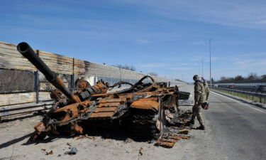 A man inspects destroyed tank of the Russian army about 40 kilometers west of Kyiv