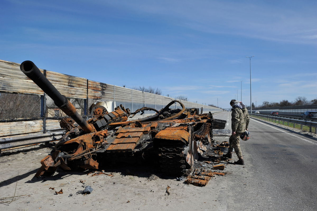 <i>Sergei Chuzavkov/SOPA Images/LightRocket/Getty Images</i><br/>A man inspects destroyed tank of the Russian army about 40 kilometers west of Kyiv