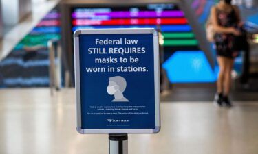 A woman walks past a sign calling for mask wearing at Penn station in New York on August 2
