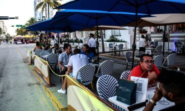People eat in the outdoor dining area of a restaurant on Ocean Drive in Miami Beach