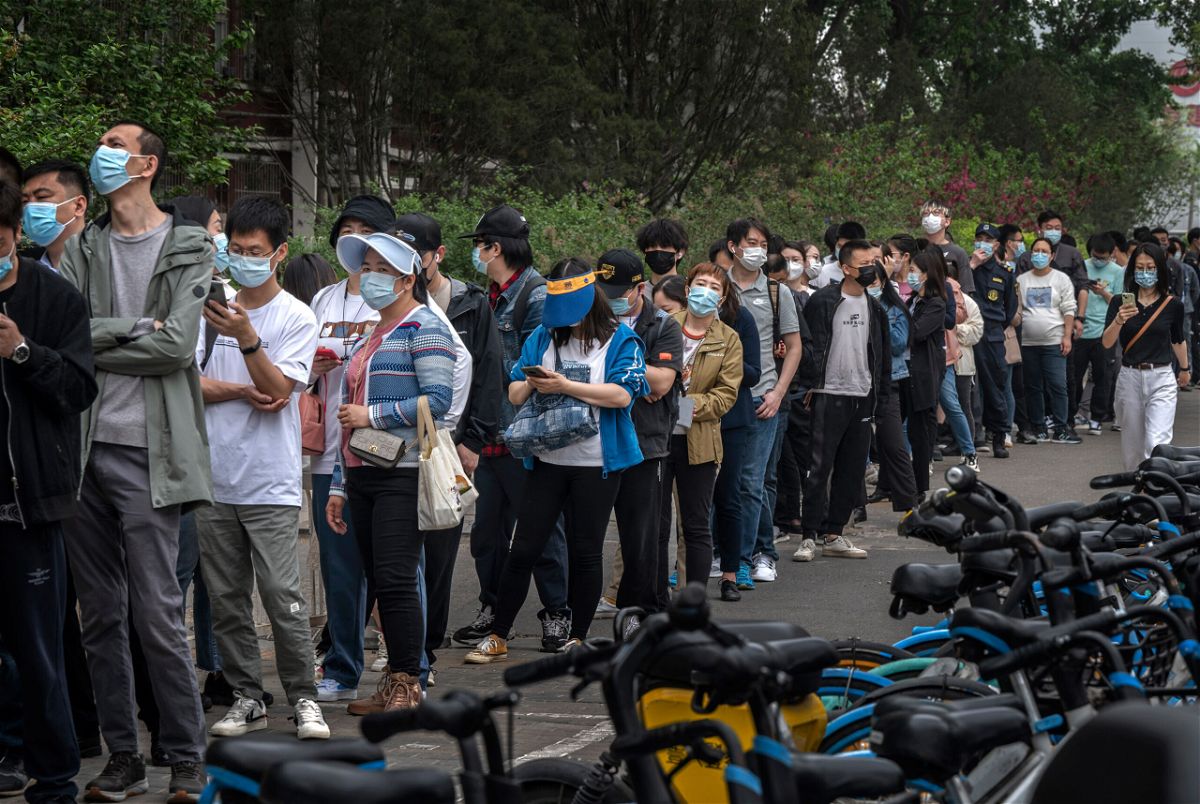 <i>Kevin Frayer/Getty Images</i><br/>People line up for Covid tests at a makeshift testing site in Beijing's Chaoyang district on Monday.