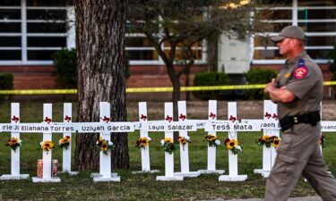 Police officers walk past a makeshift memorial for the shooting victims at Robb Elementary School in Uvalde