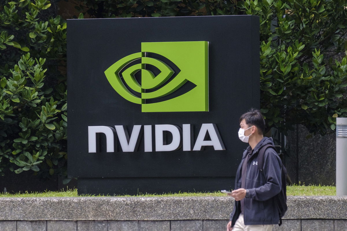 <i>Walid Berrazeg/SOPA Images/Sipa/AP</i><br/>A man wearing a mask walks past an Nvidia logo in Taipei.