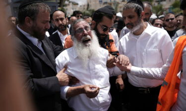 Ultra-Orthodox Jewish mourners encircle a man overcome with grief following the attack.