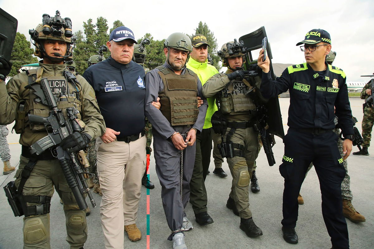 In this photo released by the Colombian Presidential Press Office, police escort Dairo Antonio Usuga, center, also known as 