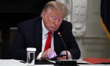 Former President Donald Trump looks at his phone during a roundtable with governors on the reopening of America's small businesses